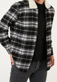 Schwarz-weiß karierte Jacke mit Reißverschluss und cremefarbenem Pelzkragen, mit langen Ärmeln und lässiger Passform.