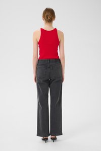 Top en maille rouge à côtes et jean noir à jambes larges, présentant une taille haute, des poches arrière et une texture lisse, vu de dos.
