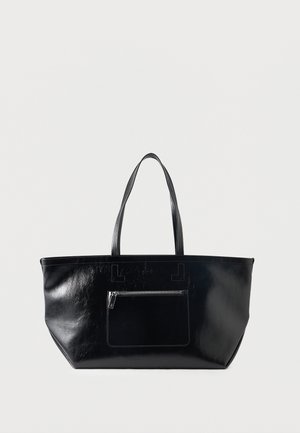 Svarte skinnveske med to håndtak og en glidelåslomme foran, vist på en ensfarget lys bakgrunn.