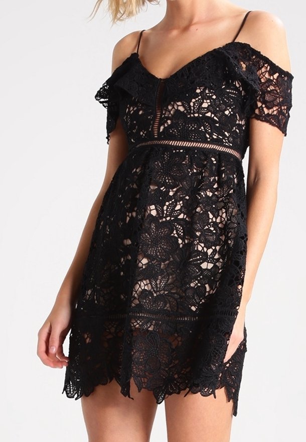 Vestido negro de encaje con detalles de volantes sin mangas, patrón floral y cintura ajustada. Tela transparente con dobladillo en forma de concha.
