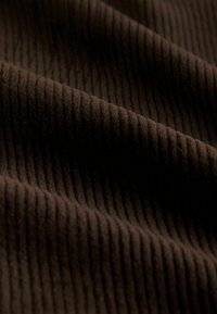 Hnědá žebrovaná tkanina s měkkou strukturou a výraznými svislými pruhy, které vytvářejí pocit hloubky a rozměru. Ideální pro čalounění.