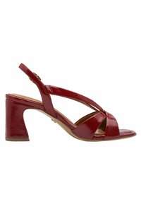 Červená sandála na podpatku se zadním páskem z lakované kůže, s překříženým páskem, otevřenou špičkou a robustním podpatkem. Hladký povrch s lesklým finišem.