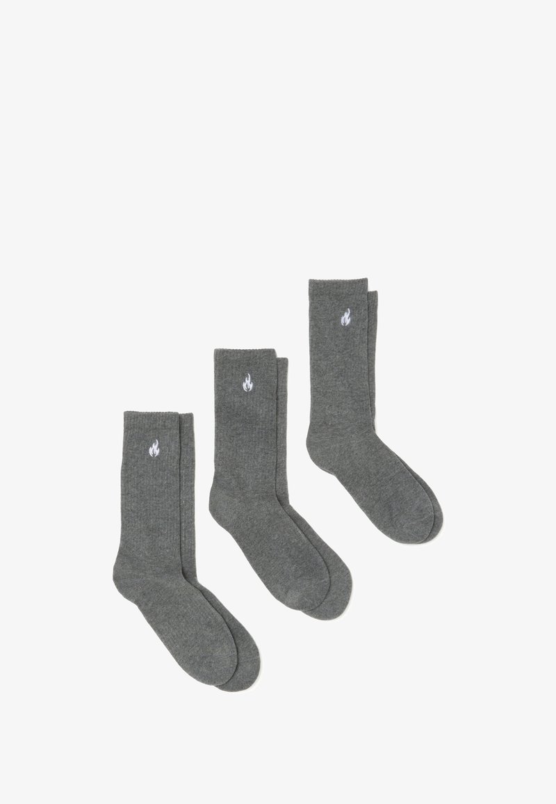 Set di tre paia di calzini in cotone grigio, con una texture morbida, altezza media e un logo a fiamma bianca su ogni calzino.