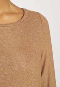 Maglione marrone a maglia con scollatura tonda e maniche lunghe, caratterizzato da un motivo a coste testurizzato e una leggera variazione di colore.