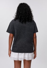 Black, short-sleeve t-shirt made of soft cotton with a faded finish. The design features a round neckline and a relaxed fit.