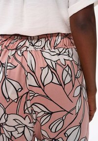 Różowe spodnie w kwiatowy wzór z czarną obwódką, z elastycznym pasem i miękką, gładką teksturą materiału.