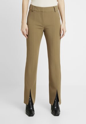 Pantalons marron ajustés avec une taille cintrée, des coutures verticales et des fentes sur les côtés, associés à des bottes à talons noires. Texture de tissu lisse.