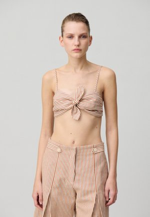 Top corto a righe marrone e beige con dettaglio annodato davanti, abbinato a pantaloni a vita alta coordinati con bottoni decorativi e pieghe.