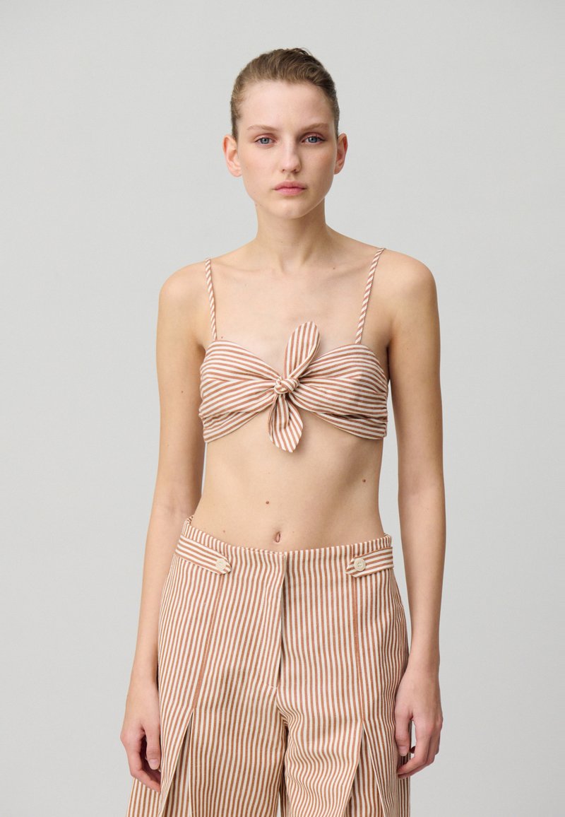 Top corto de rayas marrón y beige con detalle de nudo en el frente, combinado con pantalones de tiro alto a juego que presentan acentos de botones y pliegues.