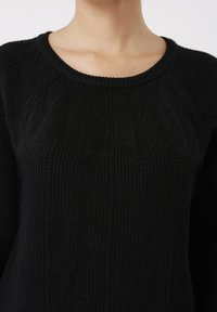 Μαύρο πουλόβερ με ριμπ ύφανση, στρογγυλή λαιμόκοψη και σχέδιο με φύλλα στο πάνω μέρος. Μαλακό πλεκτό υλικό.