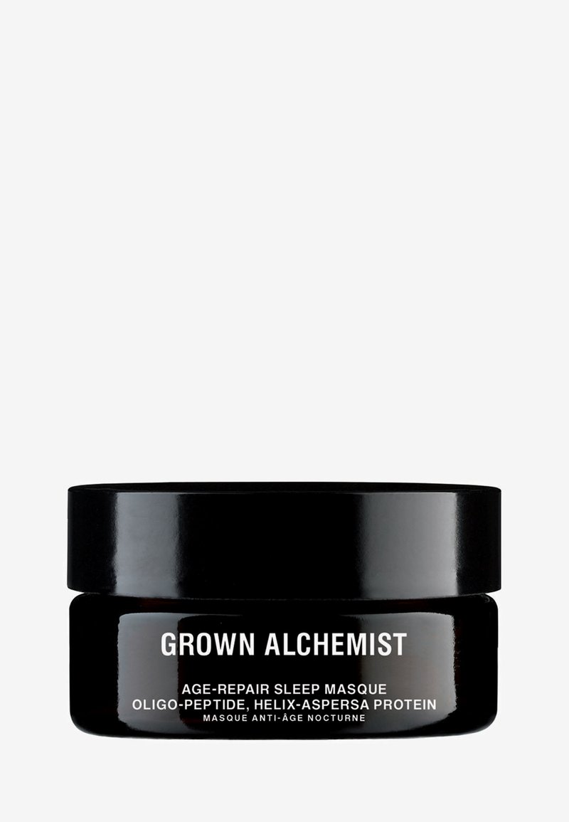Pot noir circulaire avec une finition brillante, étiqueté "Grown Alchemist Age-Repair Sleep Masque." Du texte blanc en gras détaille les ingrédients à l'avant.