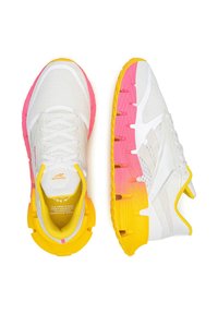 Biele bežecké tenisky Reebok s priehľadnou vrchnou časťou, so žltými a ružovými gradientnými podrážkami, vystavené zo zvrchu a zboku na bielom pozadí.