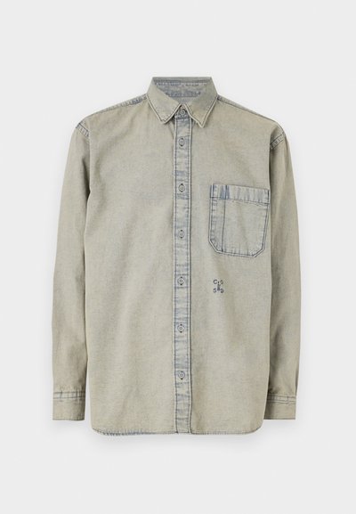 Camisa de jeans cinza claro com colarinho abotoado, mangas longas, um bolso no peito e um pequeno logótipo bordado no lado inferior esquerdo.
