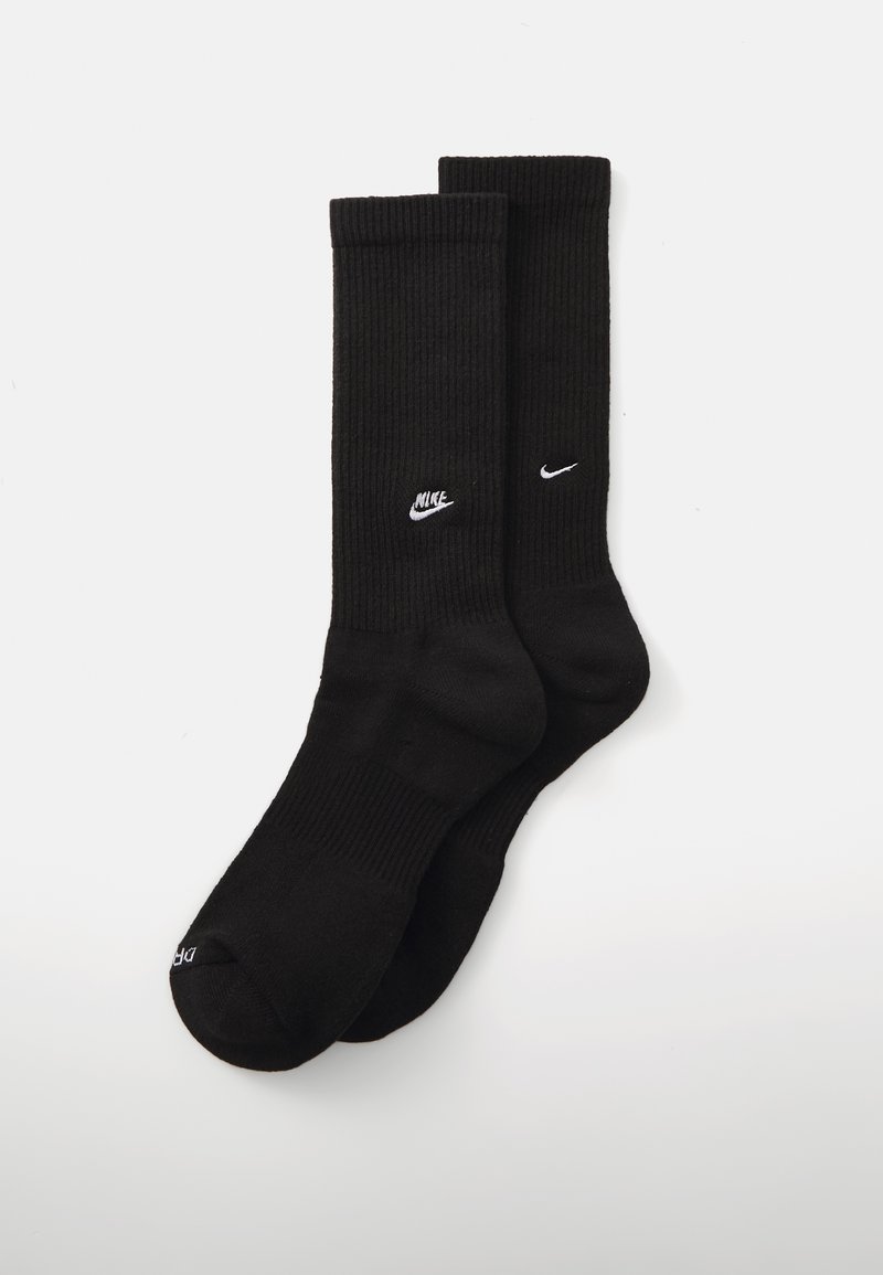 Sosete negre cu textura canelată, fabricate dintr-un amestec de bumbac, având logo-uri albe Nike pe laterale și talpă căptușită pentru confort.