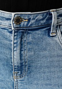 Lichtblauwe denim jeans met een knoopsluiting met zwarte hardware, riemlussen en een opvallend vervagend patroon langs de stof.
