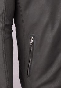 Dark gray leather jacket featuring a zippered pocket on the left side, with smooth texture and minimal stitching details.