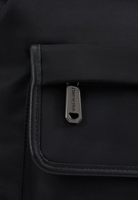 Black nylon backpack featuring a smooth texture, flap pocket, and a silver-tone zipper pull with "Valentino" engraved detail.