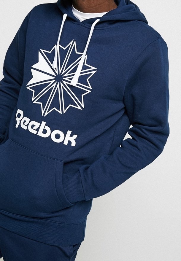 Felpa blu navy realizzata in morbido tessuto; presenta un grande logo geometrico bianco a forma di stella e il testo "Reebok" sul davanti; cappuccio con cordino regolabile.