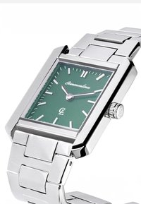 Ορθογώνιο ασημένιο μεταλλικό ρολόι με πράσινο καντράν, ασημένιους δείκτες ωρών, λεπτών και ωρών, και μπρασελέ με μεταλλικούς κρίκους.