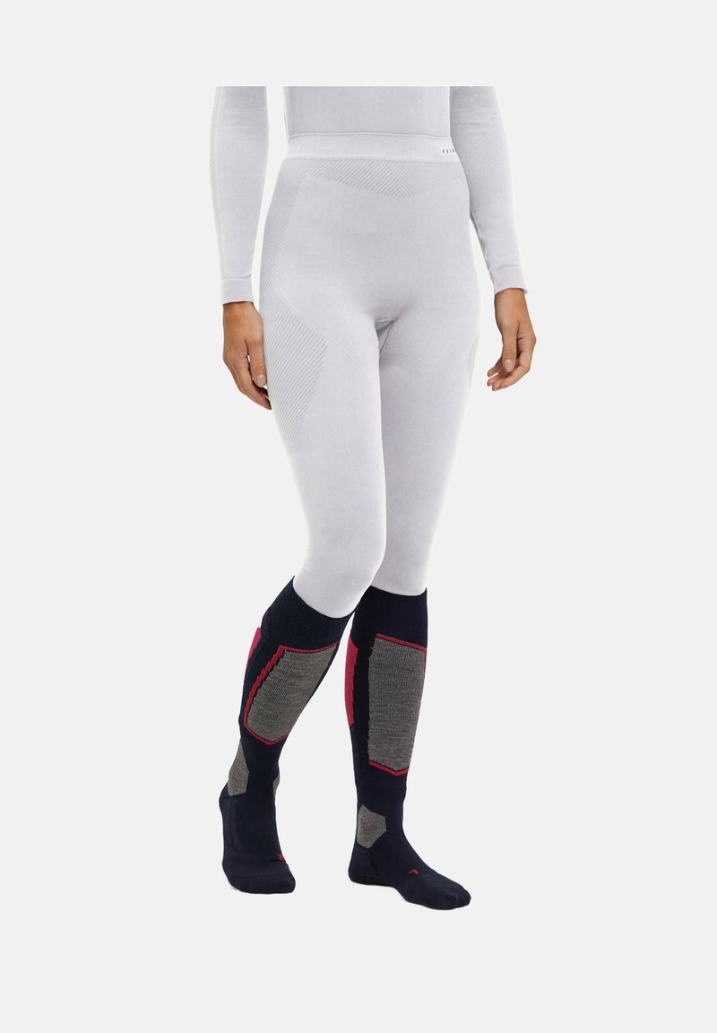 Witte thermoleggings met een gestructureerde tailleband, gecombineerd met marineblauwe kniekousen met grijze panelen en rode accenten.