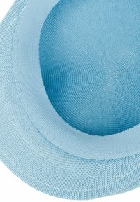 Cappello di tessuto azzurro chiaro con una forma arrotondata e una larga visiera piatta. La texture è liscia con cuciture dettagliate lungo i bordi.