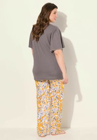 Camiseta gris con mangas abullonadas combinada con pantalones amarillos de estampado floral. El tejido suave y el corte holgado brindan comodidad. El diseño minimalista acentúa los estampados.