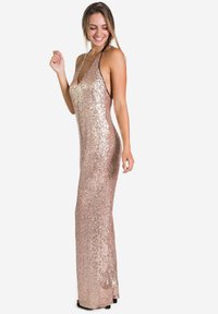 Robe en sequins rose gold avec une silhouette ajustée, décolleté plongeant, dos nu et bretelles halter. Longueur au sol, texture scintillante, design moulant.