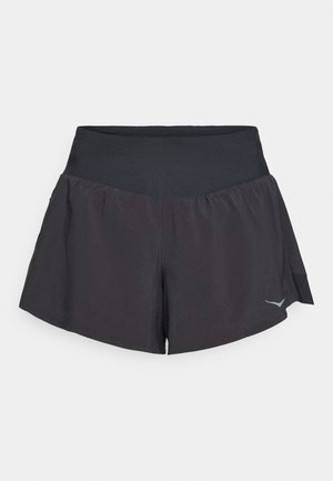 Sorte idrettsshorts med en bred, glatt livlinje. Har et flagrende design og en reflekterende logo på nedre høyre side.