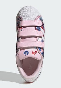 Roza superga z vzorcem cvetja, belim gumijastim ščitnikom na prstih, zapenjanjem na ježka in teksturirano tekstilno zgornjo stranjo. Ponaša se s vezenim motivom.