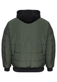 Pufferjakke i olivengrønn med svart hette. Har et kviltet design, ribbestrikkede mansjetter og en litt cropped passform i midjen.