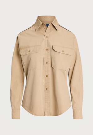 Camicia beige a maniche lunghe in cotone, con chiusura a bottoni, due tasche sul petto e colletto classico. Tessuto liscio, orlo curvo.