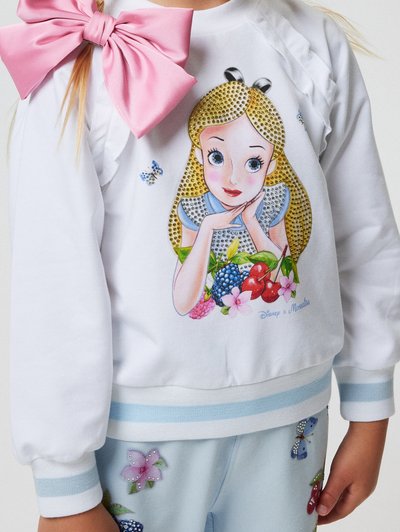 Felpa bianca con una stampa che raffigura un personaggio circondato da frutti colorati. Include un grande fiocco di raso rosa e dettagli decorativi.