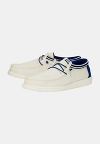 Scarpe in tela con tomaia crema, dettagli blu navy, punta rotonda e suola in gomma bianca; presentano lacci a contrasto e colletto a righe.