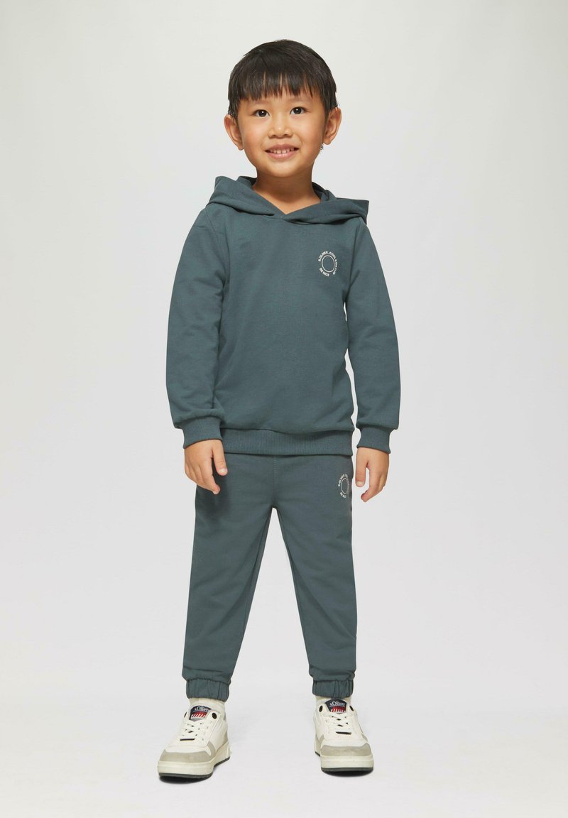 een aqua kleurige hoodie en bijpassende joggingsbroek, beide van zachte stof met een losse pasvorm. De hoodie heeft een voorvak en geborduurde details.