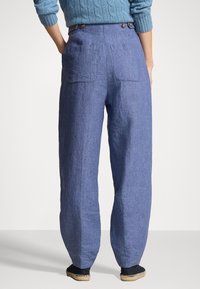 Volné modré lněné kalhoty s vysokým pasem, dvěma zadními kapsami a knoflíkovými detaily, s hladkou texturou a rovnými nohavicemi.