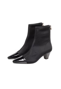 Bottines noires en tissu lisse avec un bout pointu noir brillant et un petit talon épais. Comprend une fermeture éclair sur le côté pour un accès facile.