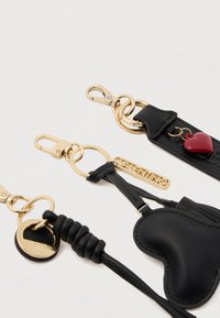 Μαύρα δερμάτινα μπρελόκ διαθέτουν χρυσά αξεσουάρ, συμπεριλαμβανομένου ενός κλιπ αστακού και δαχτυλιδιών. Ένα μπρελόκ έχει σχήμα καρδιάς και κόκκινο γούρι.