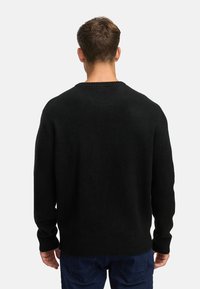 Musta neule, jossa on pyöre�ä kaula-aukko, pitkät hihat sekä ribbireunukset hihansuissa ja helmassaan. Neuleessa on pehmeä rakenne ja rento istuvuus.