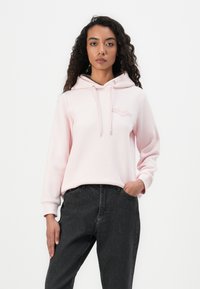 Sudadera rosa claro hecha de un tejido suave, cuenta con un bolsillo tipo canguro, capucha ajustable con cordón y un sutil logo bordado en el pecho.