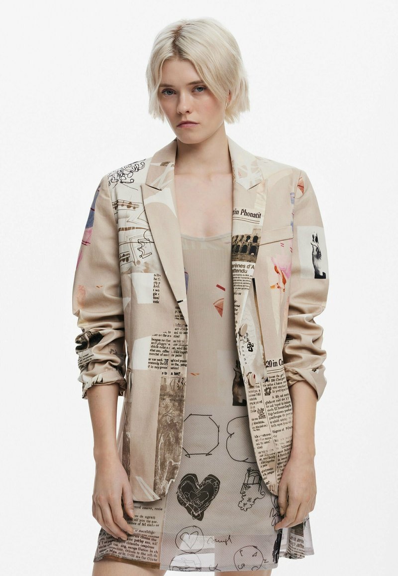 Beige blazer with mixed media prints including text, illustrations, and abstract designs. Smooth texture, single-breasted style with rolled sleeves.