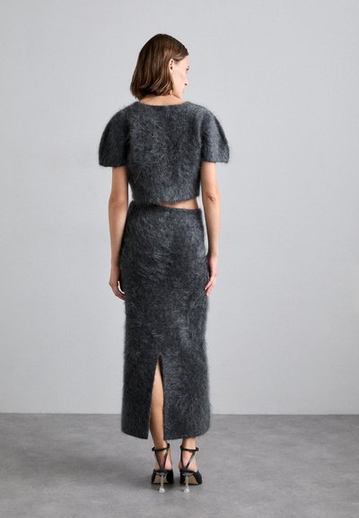 Grijs, fluffy twee-delige set met korte puffmouwen, een cropped top en een lange rok met een split aan de achterkant. Gestyld met zwarte hakken.