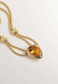 Collar de tono dorado con cadena trenzada y un centro de gema de ámbar en forma de pera, que presenta un engaste texturizado.