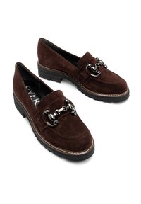 Brązowe zamszowe mokasyny z czarnym akcentem w postaci łańcucha, z grubą podeszwą i przeszyciami wzdłuż krawędzi. Płaskie, wsuwane buty.