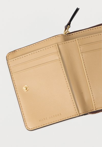 Interno di portafoglio in pelle beige con molteplici scomparti per carte, chiusura a scatto e logo del marchio in rilievo. Texture liscia e design minimalista.