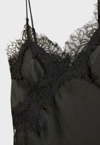 Sort satin cami med delikate blondekanter langs udskæringen, med nedslidte kanter og justerbare spaghettistropper.