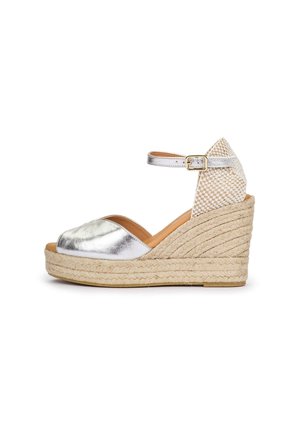 Keil-Espadrillesandalette mit silber-metallischer Vorderseite, gewebter beiger Knöchelstütze, verstellbarem silbernem Riemen und geflochtener Schnur-Plateausohle.