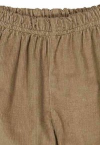 Beige ribfluwelen broek met een elastische tailleband, voorzien van verticale ribbels en een zachte textuur. Geen zichtbare zakken.