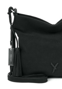 Borsa nera in pelle con texture perforata, forma morbida e dettaglio a croce. Presenta un'etichetta metallica e una tracolla lunga con un dettaglio a frangia.