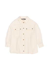 Chaqueta oversized de color crema hecha de tela texturizada. Presenta un cierre frontal con botones, dos bolsillos en el pecho y un cuello. Botones en tono dorado como detalle.