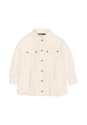 Kremowa, oversize'owa kurtka wykonana z teksturowanej tkaniny. Posiada zapinanie na guziki z przodu, dwie kieszenie na piersi oraz kołnierz. Akcent w postaci złotych guzików.